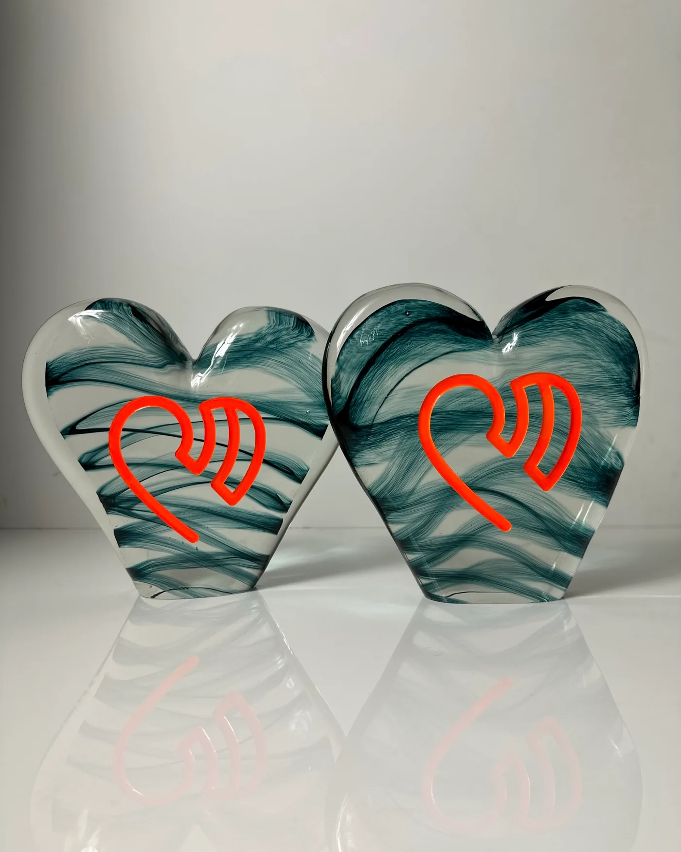 Two clear glass heart awards with teal swirls, each with the Endotronix heart logo engraved and filled with orange enamel