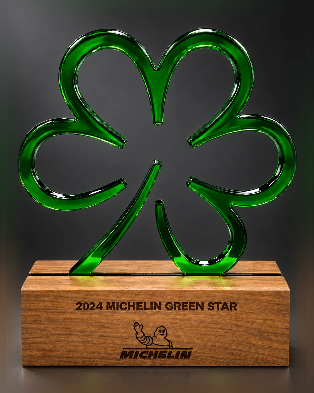 Green glass four-leaf clover award for Daisies standing in a walnut base engraved 2024 Michelin Green Star