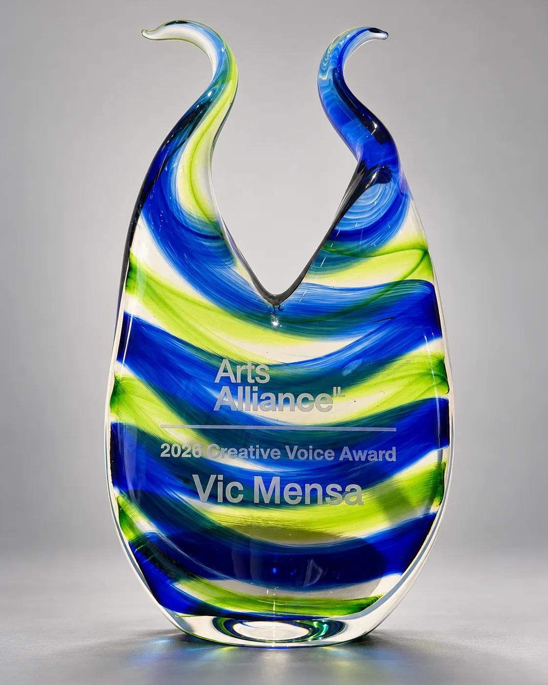 Blue, green and yellow double-neck glass award with Arts Alliance lettering and Vic Mensa’s name.